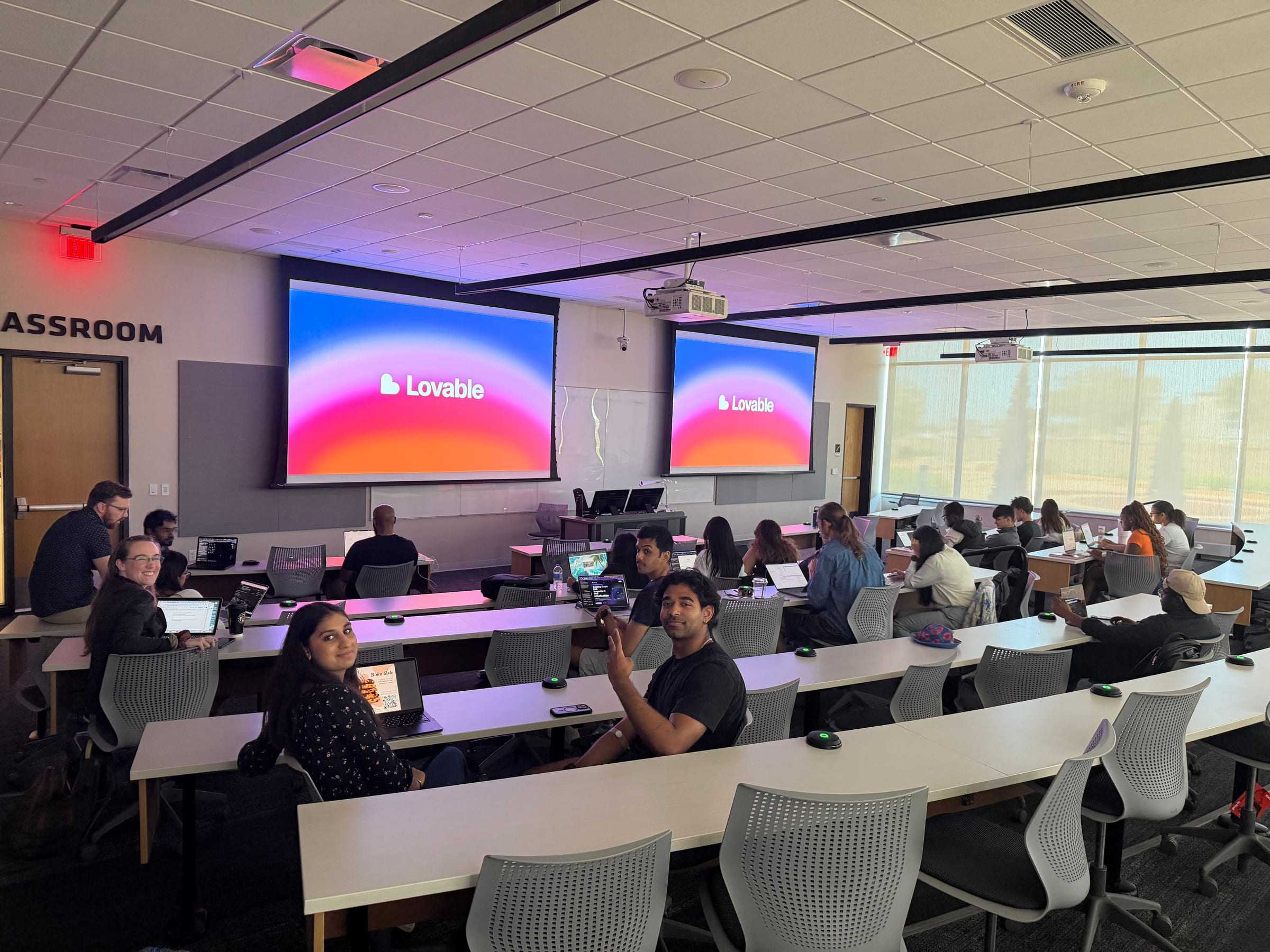 Students on laptops in a lecture hall during the Lovable workshop, with the Lovable logo on both screens.